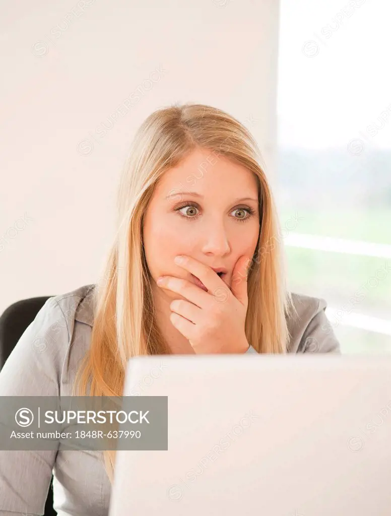 Young woman working on computer, puzzled