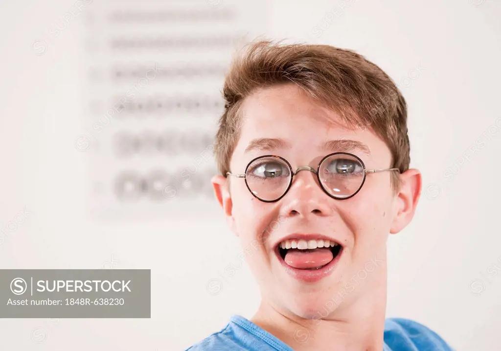 Teenage boy, portrait wearing thick-glassed glasses in front of a sight test