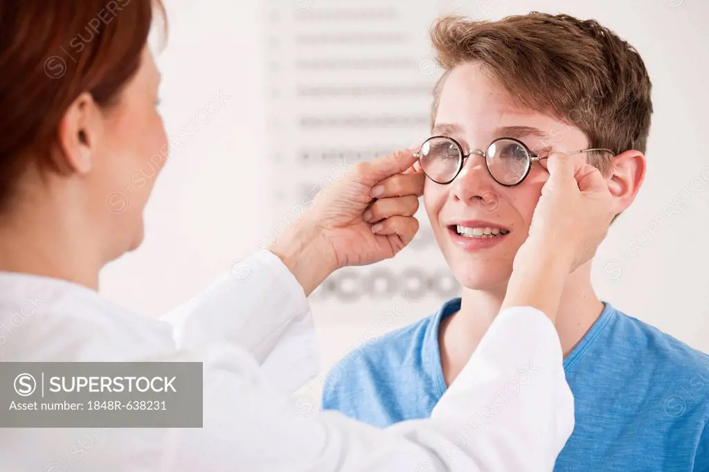 Ophthalmologist putting a pair of glasses on a teenage boy