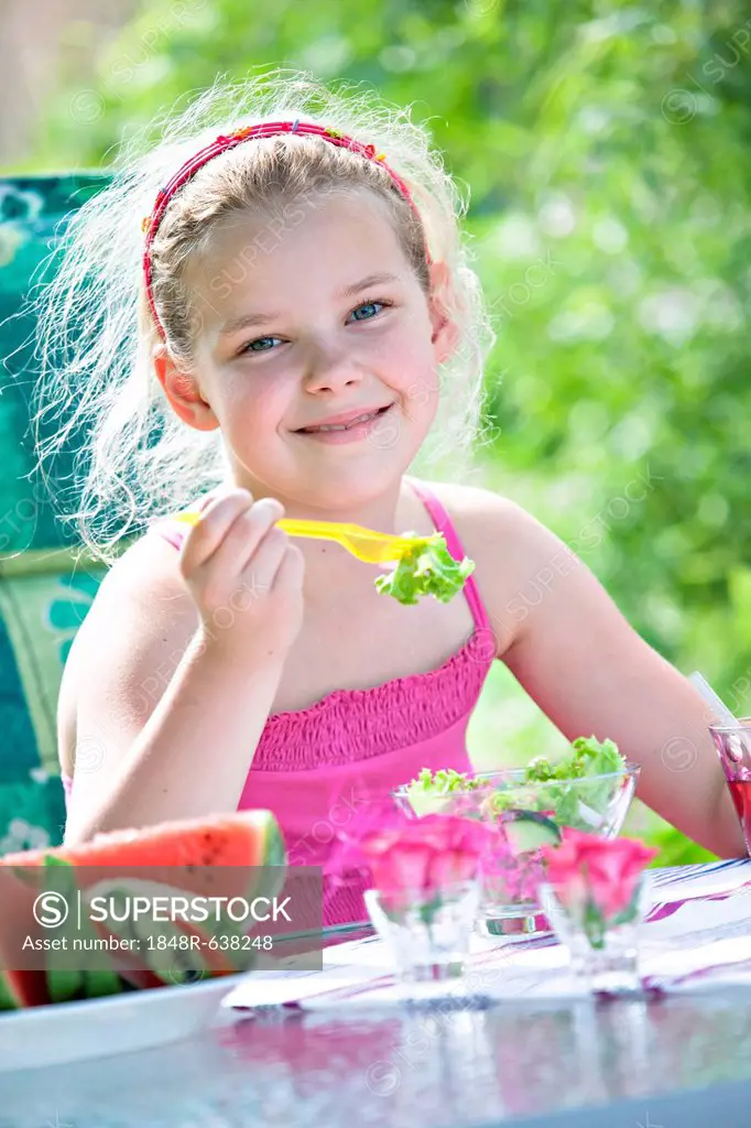 Girl eating salad at a garden table