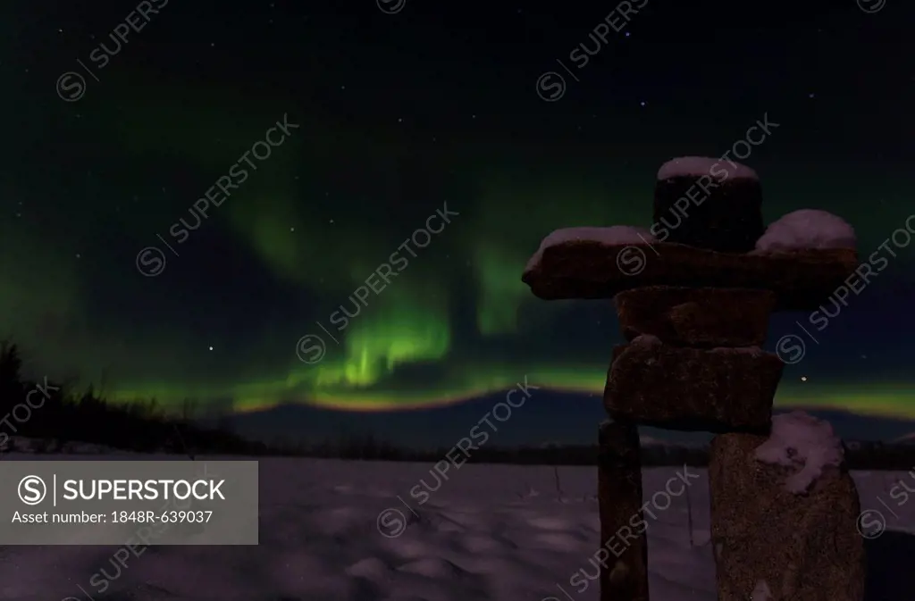 Silhouette of Inuit stone man, inukshuk, inuksuk, stone landmark or cairn, Northern lights, Polar aurora or Aurora Borealis, green, near Whitehorse, Y...
