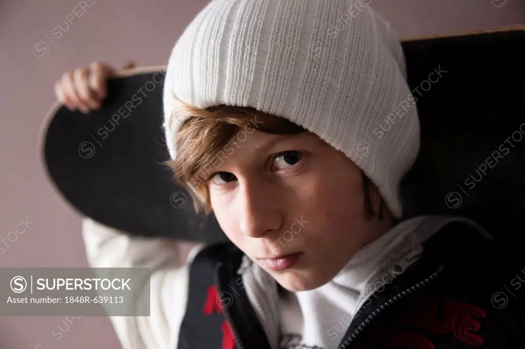 Cool boy wearing a cap and holding a skateboard