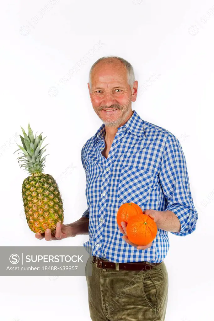Elderly man holding a pineapple and oranges in his hands