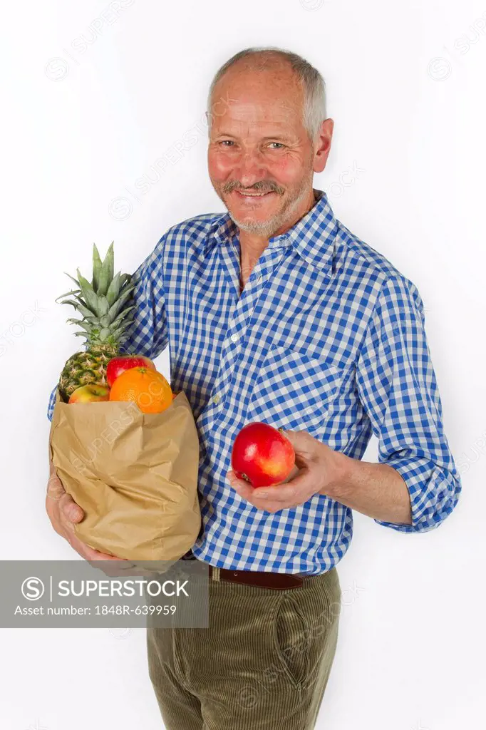 Elderly man with a bag of fruit and an apple in his hand