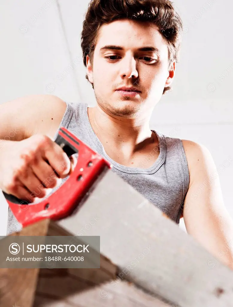 Young man sawing a wooden beam