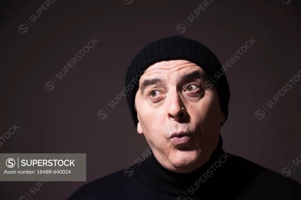Elderly man wearing a black woollen hat, with a surprised look