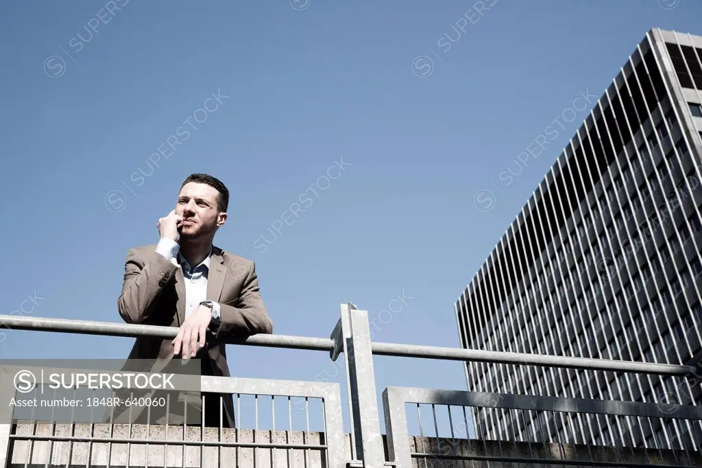 Young business man standing pensively against a railing