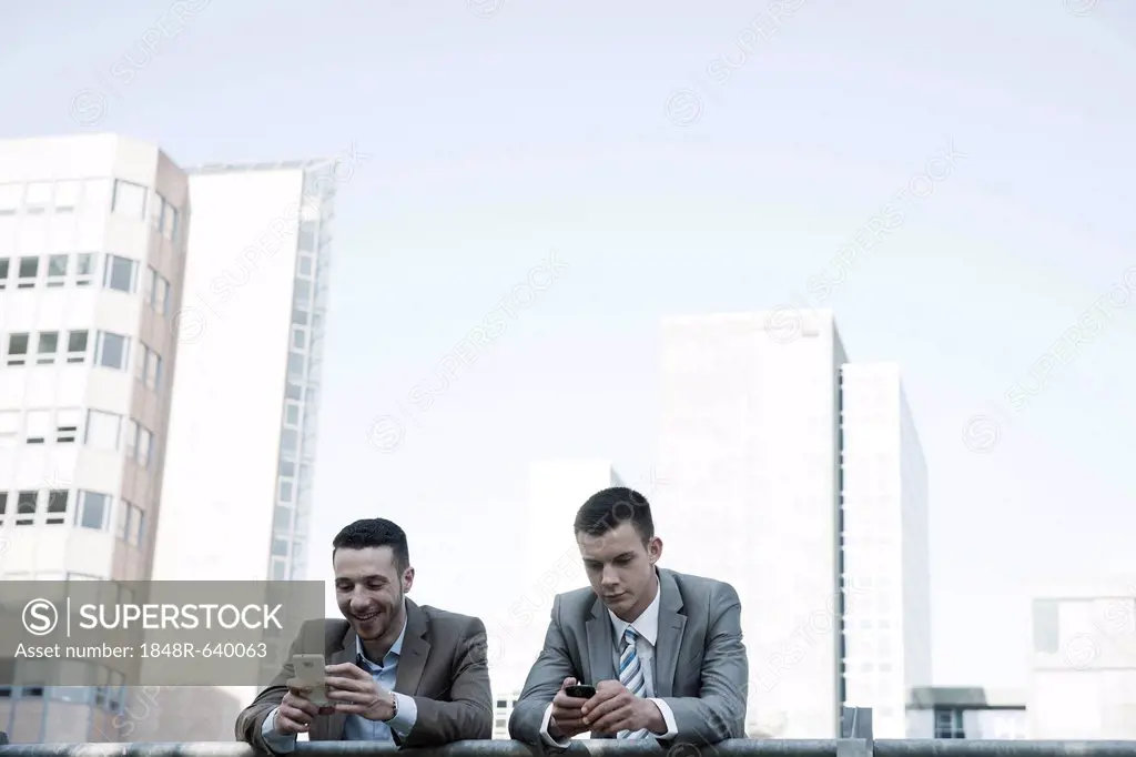 Two managers checking their smartphones during a break