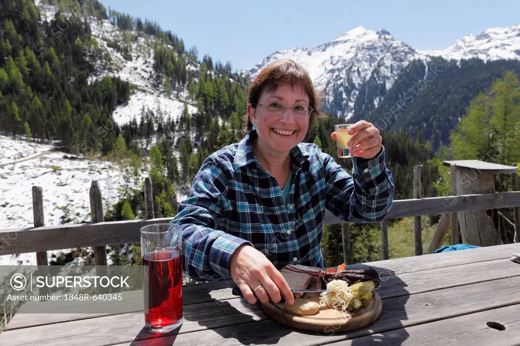 Woman eating a bacon snack and drinking mead at Gfoelleralm restaurant, Soelktaeler Nature Park, Schladming Tauern mountains, Upper Stryria, Styria, A...