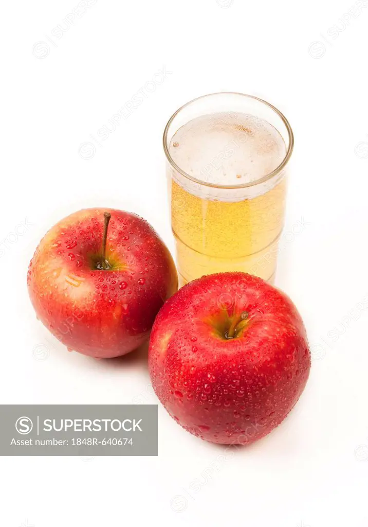 Two apples beside a glass of apple juice