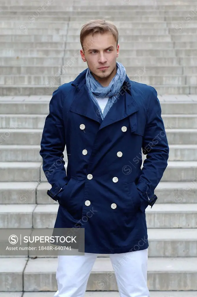 Fashion image, young man wearing a blue coat standing on an outside staircase