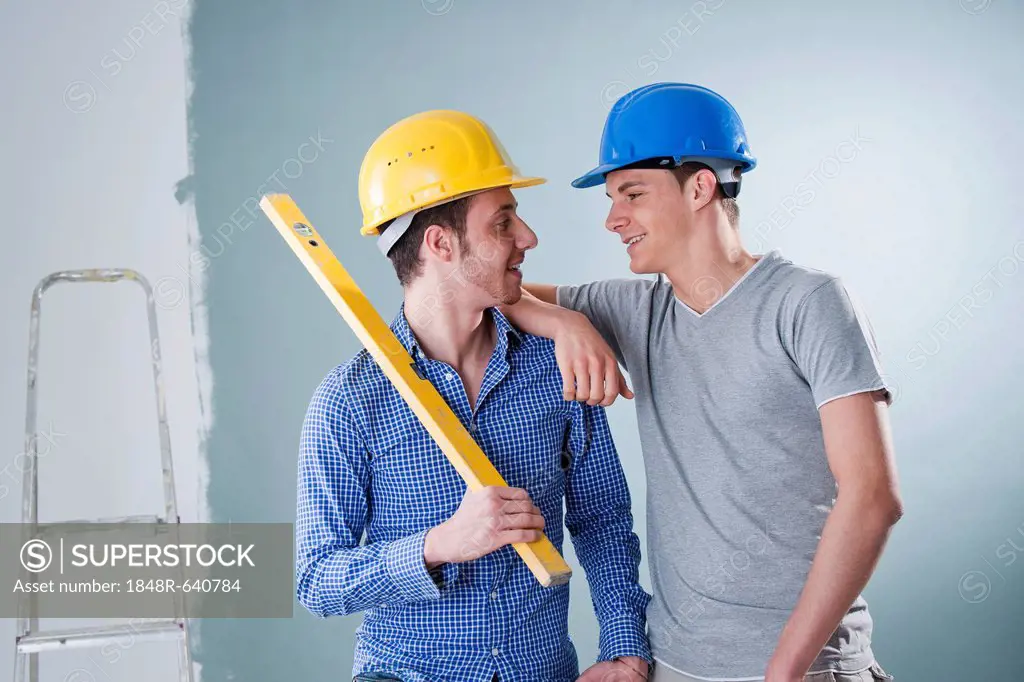 Two young tradesmen holding a spirit level