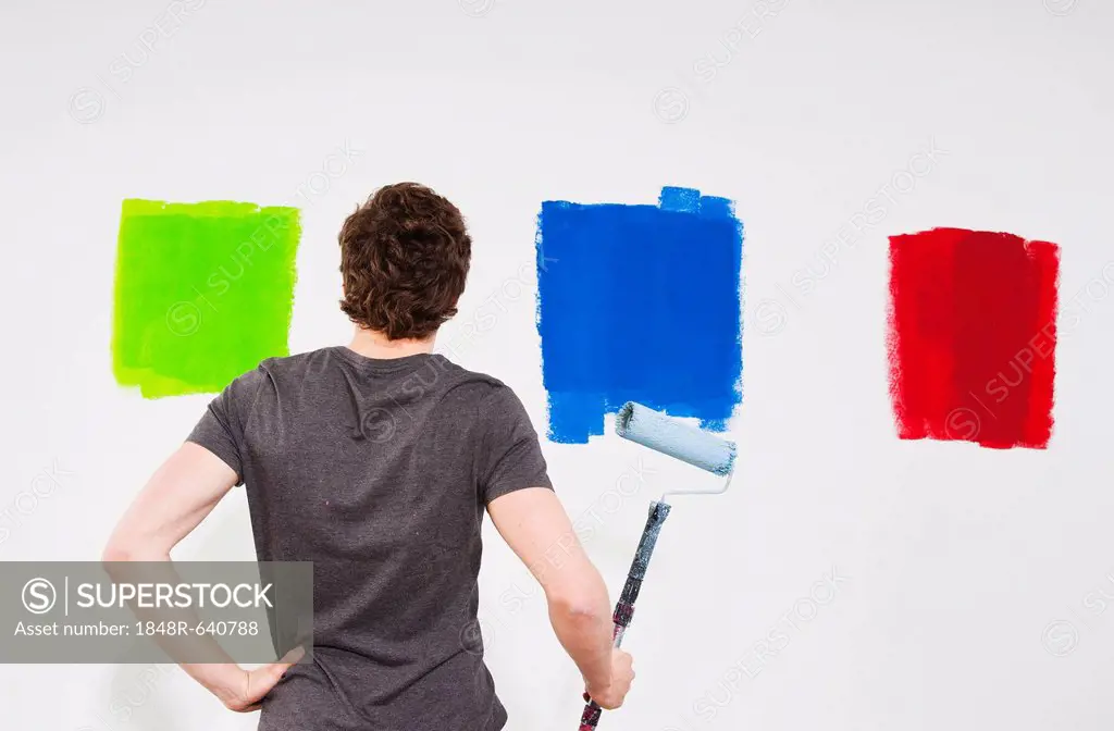 Young man painting a wall with paint samples