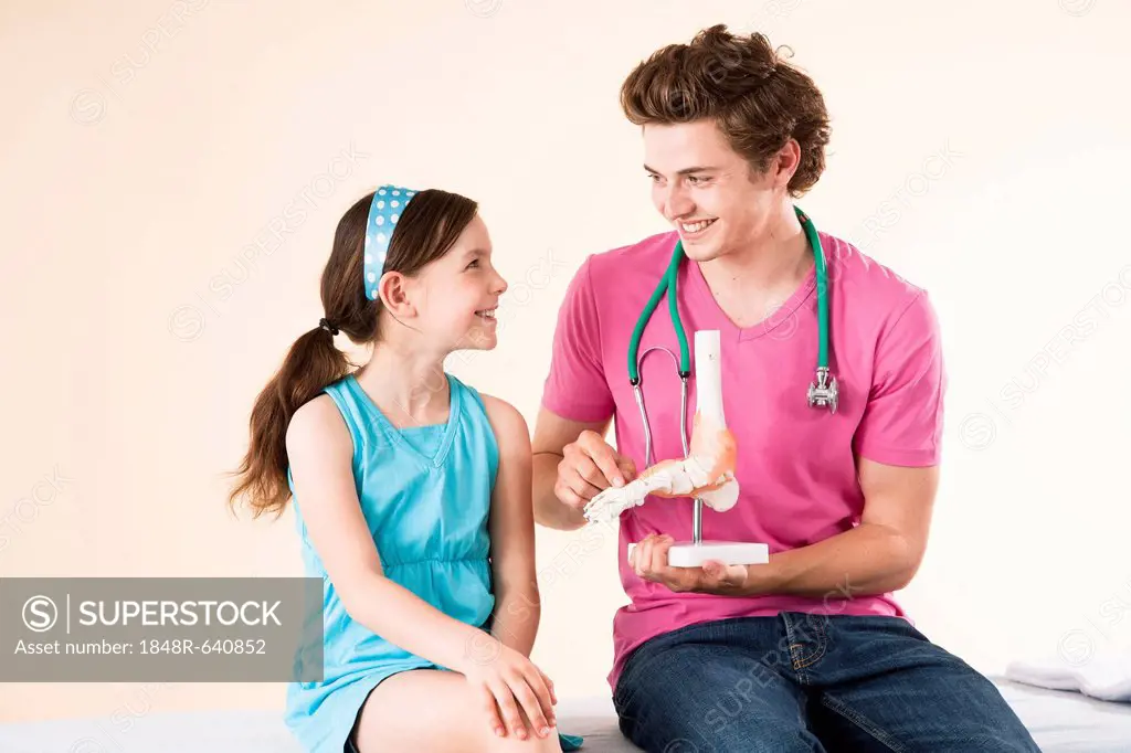 Doctor explaining a model of a foot to a girl