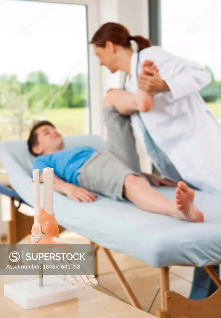 Orthopedic surgeon examining a teenage boy's injured leg