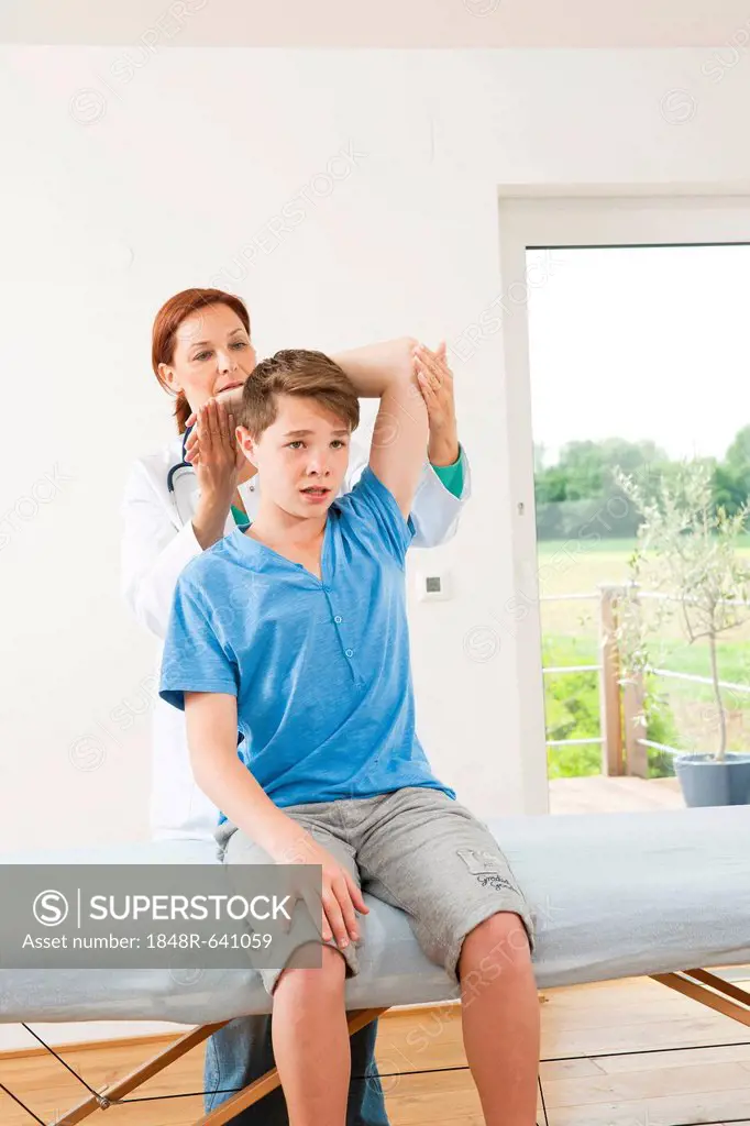 Physiotherapist doing physiotherapy in the shoulder area of a teenage boy