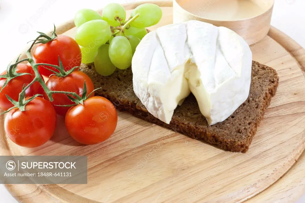 Chardonnay cheese on a board with grapes, tomatoes and bread