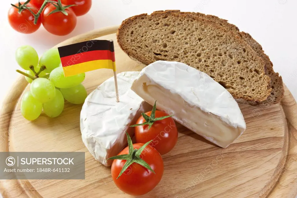 German Camembert chees on a board with grapes, bread and tomatoes