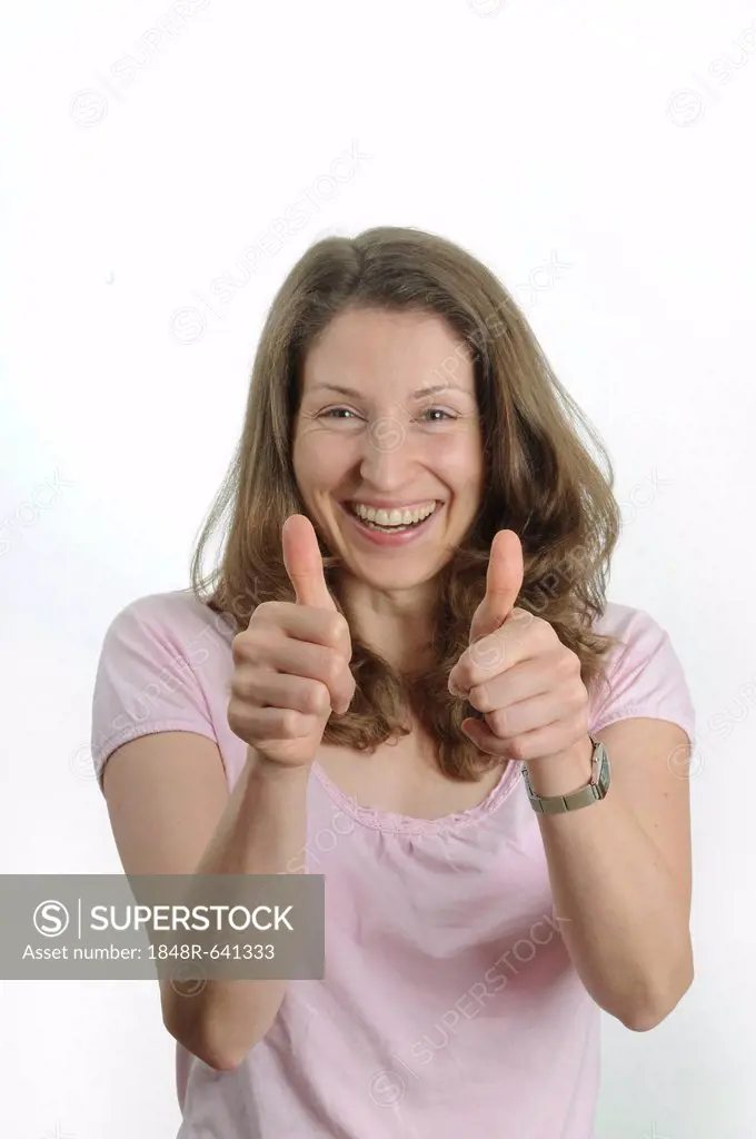Young woman making thumbs-up gesture, smiling