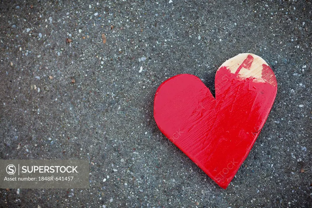 Red wooden heart on asphalt