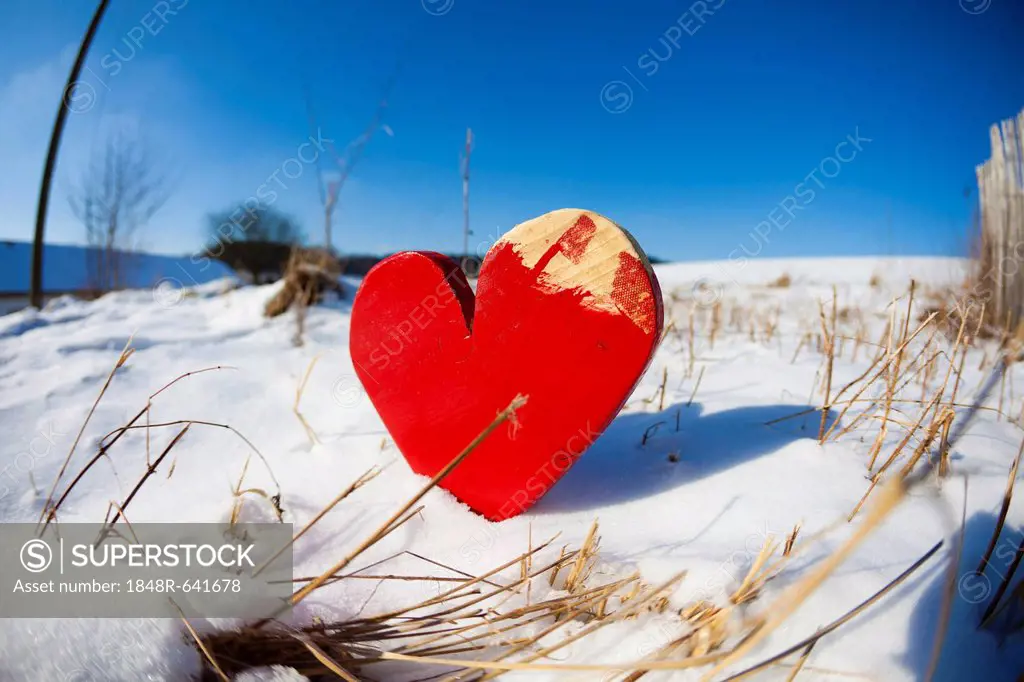 Red wooden heart in the snow