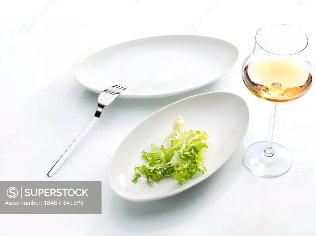 Lettuce leaf on a plate, fork, wine glass