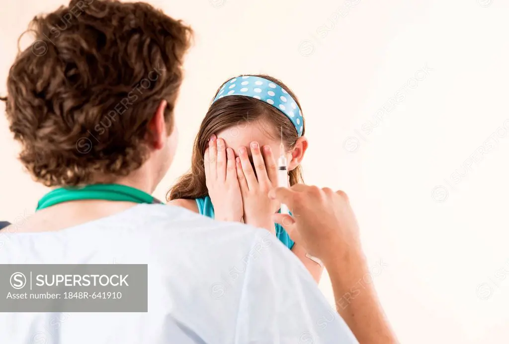Girl being afraid of a syringe held by her pediatrician