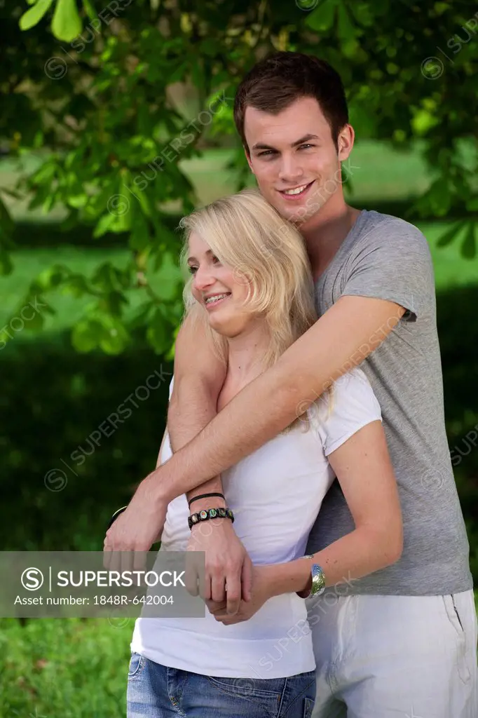 Young man embracing a young woman in a park in spring