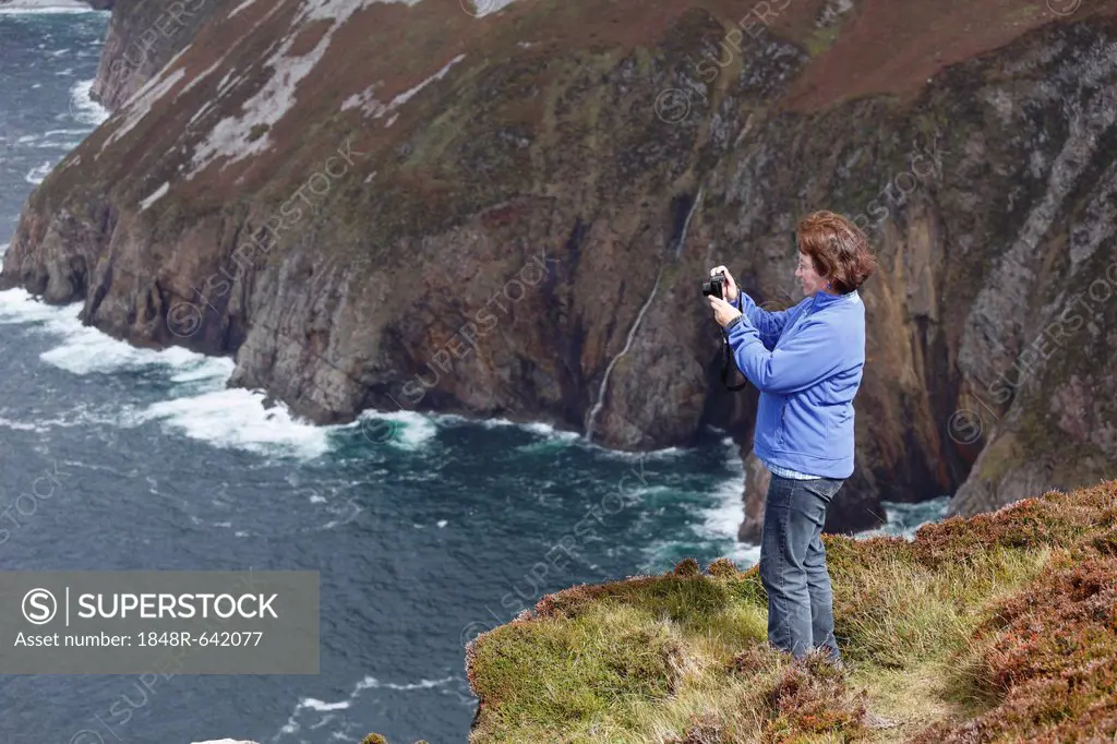 Woman taking pictures with a digital compact camera, at the cliffs of Slieve League, County Donegal, Ireland, Europe