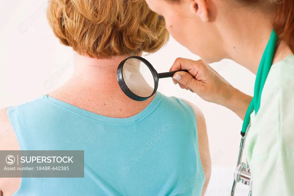 Dermatologist examining a patient with a magnifying glass