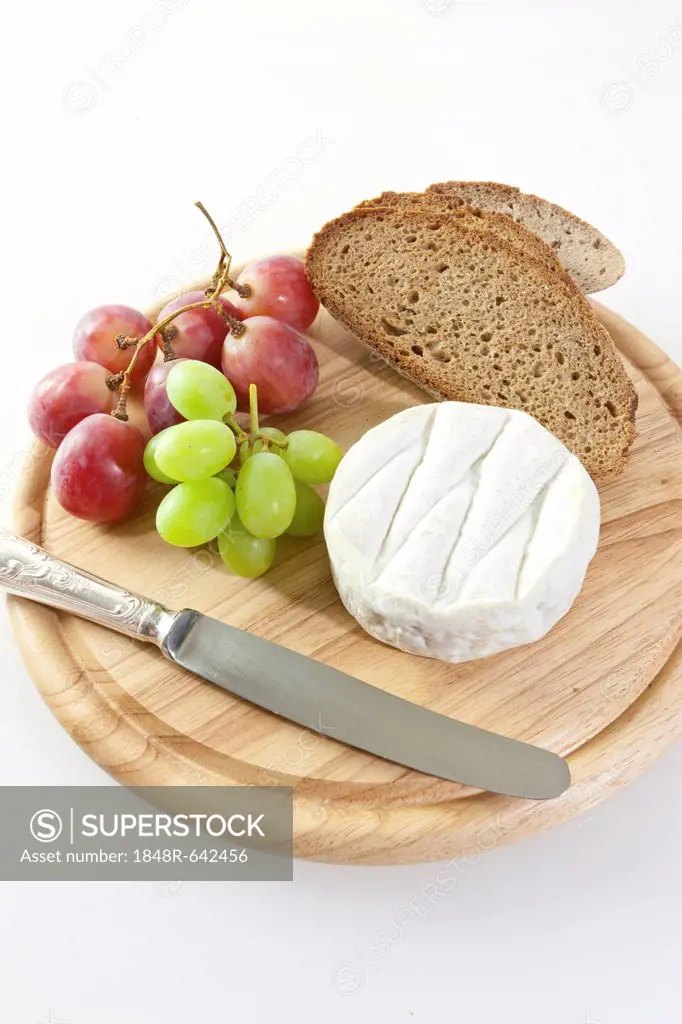 Chardonnay cheese on a board with grapes and bread