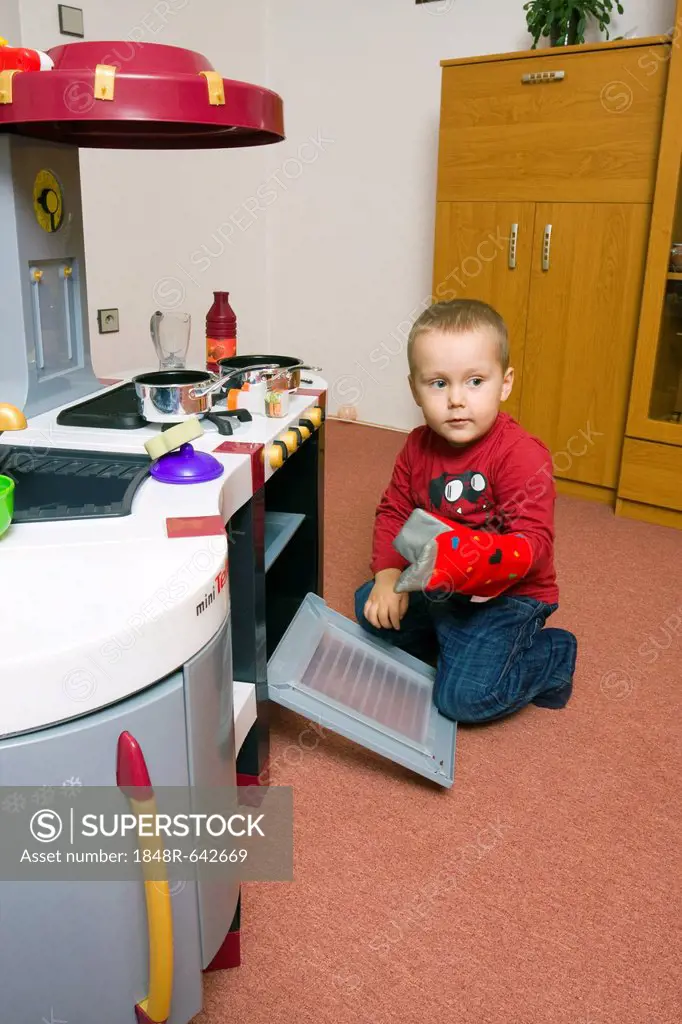 Boy, 2 years, playing with toy kitchen