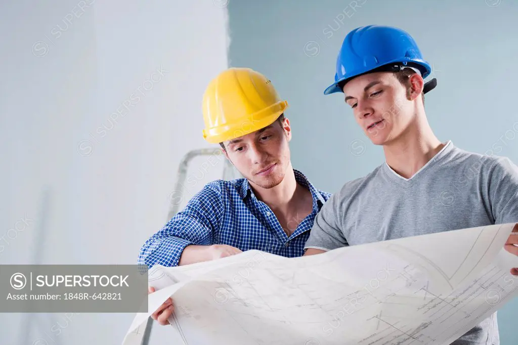 Two young tradesmen looking at a building plan