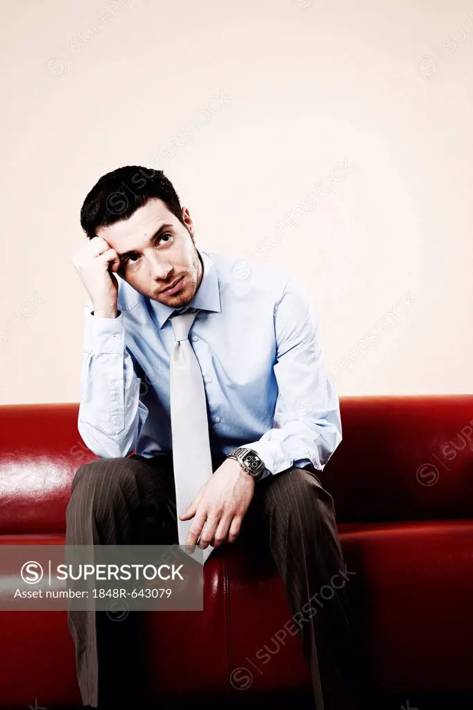 Young man sitting pensively on a sofa and waiting