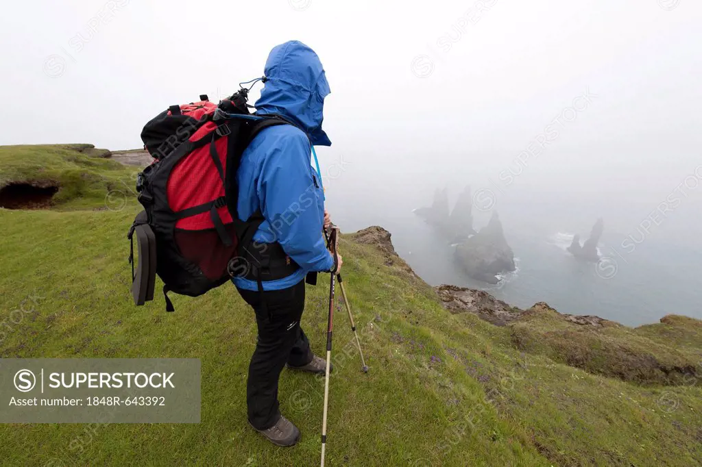 Female hiker standing at the cliffs of Vik, Iceland, Europe