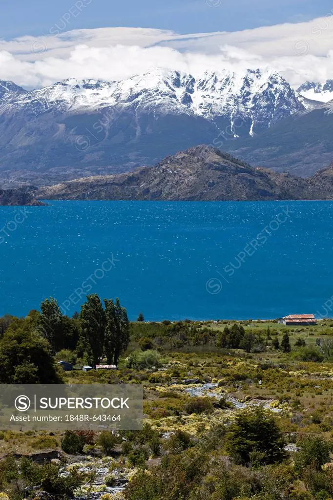 A lonely farmhouse on the deep blue lake Lago General Carrera, the snow-capped Andes at the back, Carretera Austral, Ruta CH7 road, Panamerican Highwa...