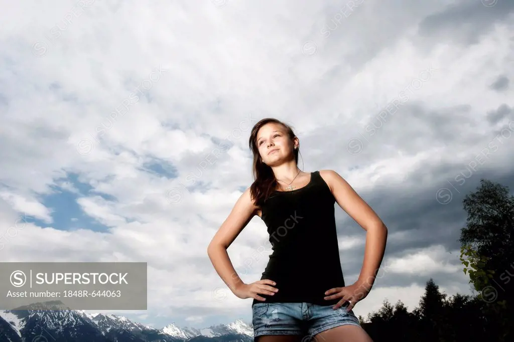Girl, 14 years, looking up thoughtfully, in front of cloudy sky, Tyrol, Austria, Europe