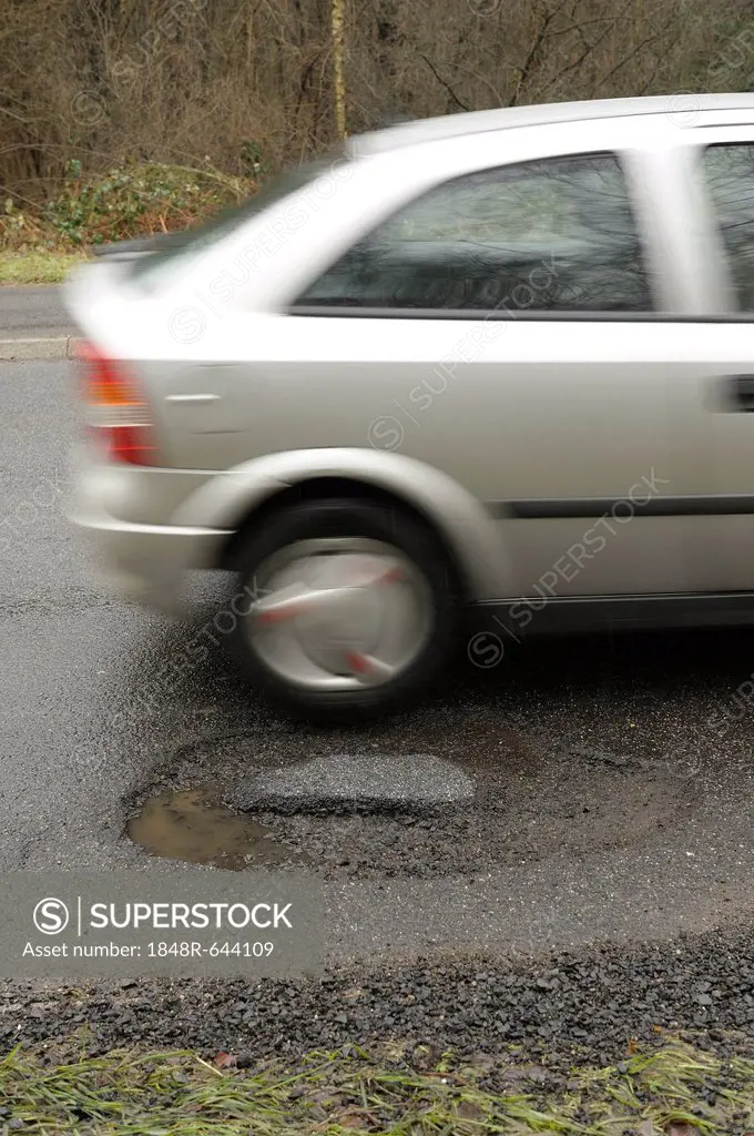 Car driving past a pothole, Bergisch Gladbach, North Rhine-Westphalia, Germany, Europe