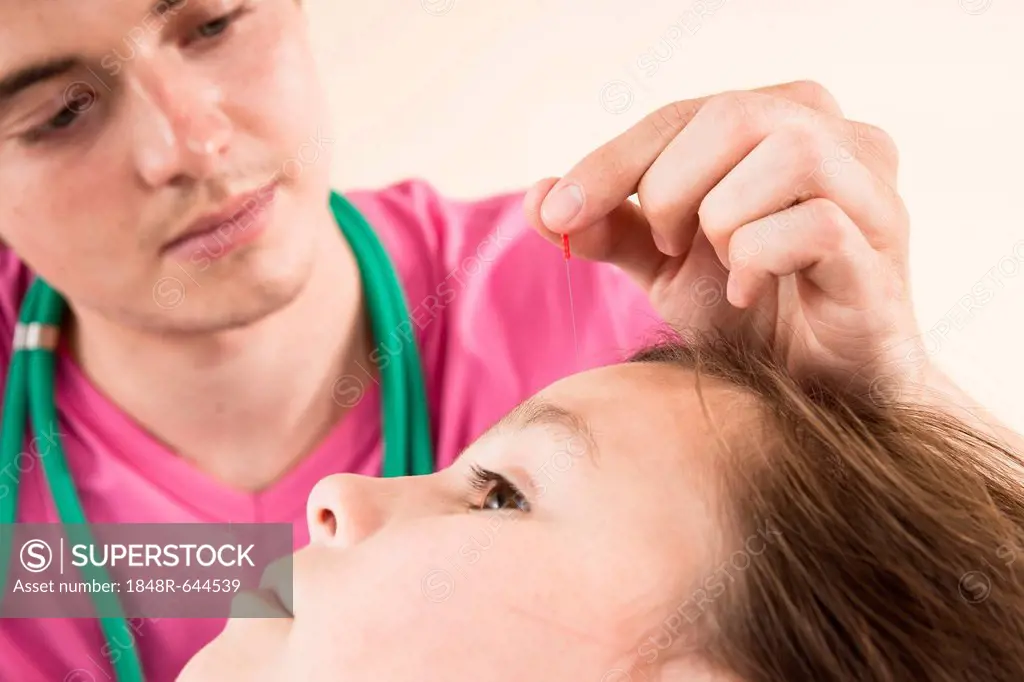 Pediatrician treating a young girl with acupuncture