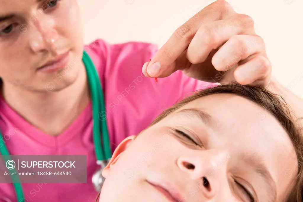 Pediatrician treating a young girl with acupuncture