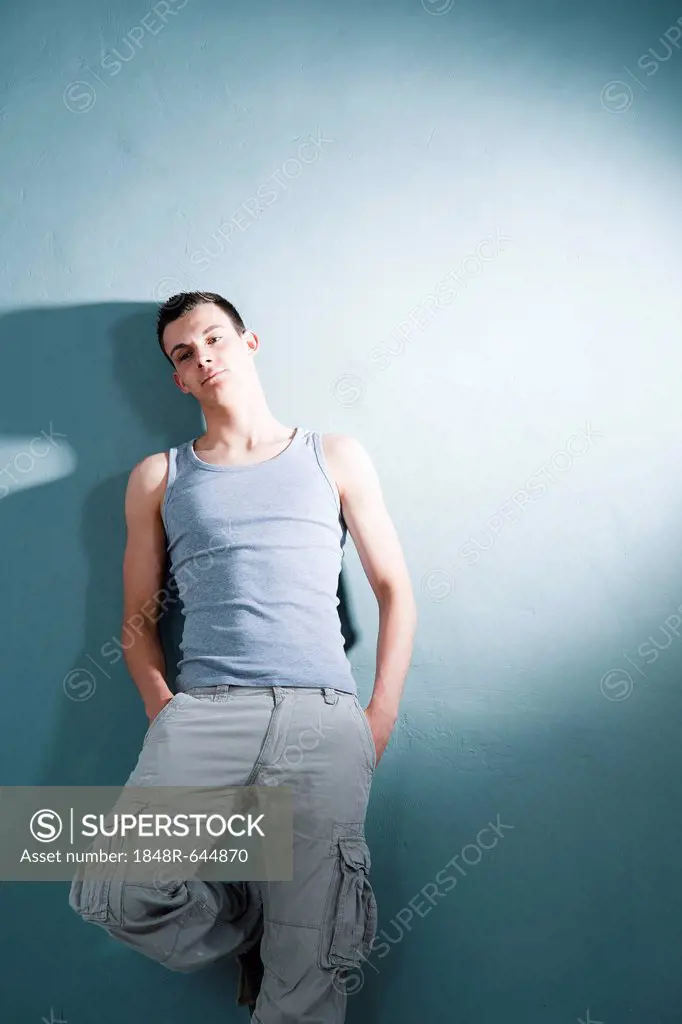 Cool young man wearing a singlet, leaning against a wall