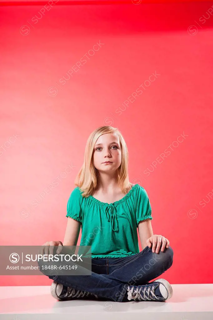 Girl sitting cross-legged with a serious expression