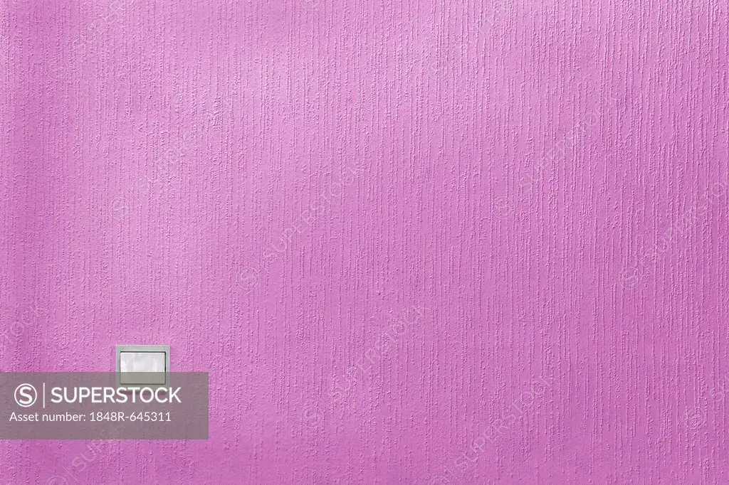 Light switch on a wall with pink textured wallpaper