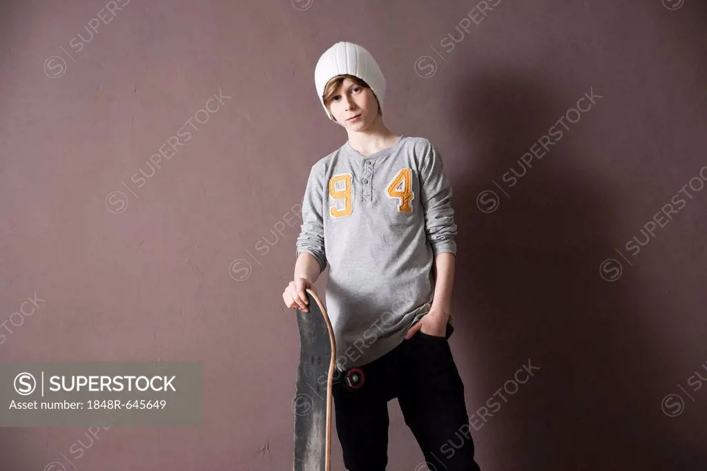 Cool boy wearing a cap and holding a skateboard