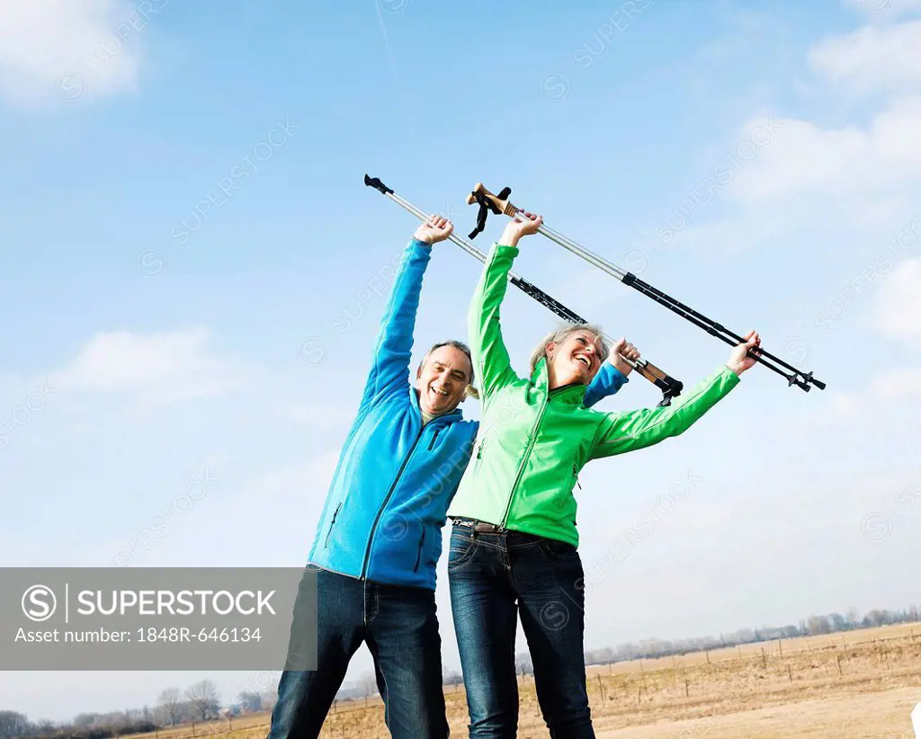 Senior couple doing exercises with walking sticks in a field