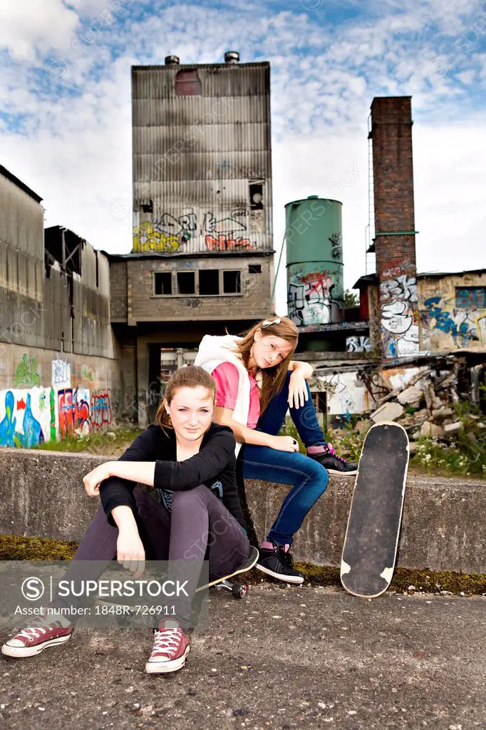 Two young teenage girls with skateboards in an urban area