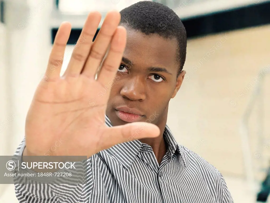 Young man, African-American, American, raising his hand to stop someone, unapproachable, distance