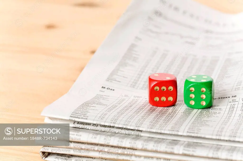 Red and green dice on a newspaper with stock prices
