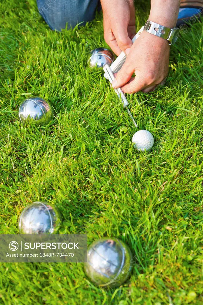 Man playing boules, petanque, measuring the distances between the balls, Hesse, Germany, Europe