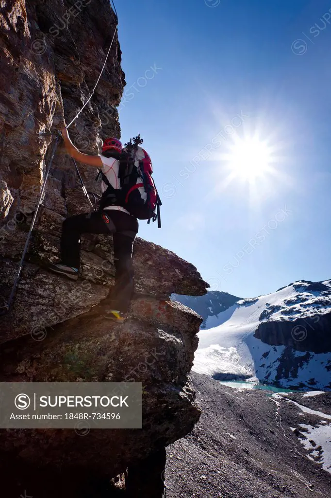 Hiker climbing to the top of Tschenglser Hochwand, on the fixed rope route, above Duesseldorfhuette mountain lodge in Sulden, Kleiner Angulus at the b...